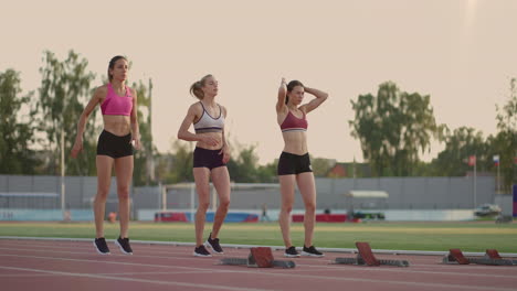 Tres-Atletas-Femeninas-Comienzan-Simultáneamente-A-Correr-Maratón-Rivalidad-En-Cámara-Lenta.-Mujeres-Paradas-En-Una-Línea-De-Salida-Antes-De-La-Carrera